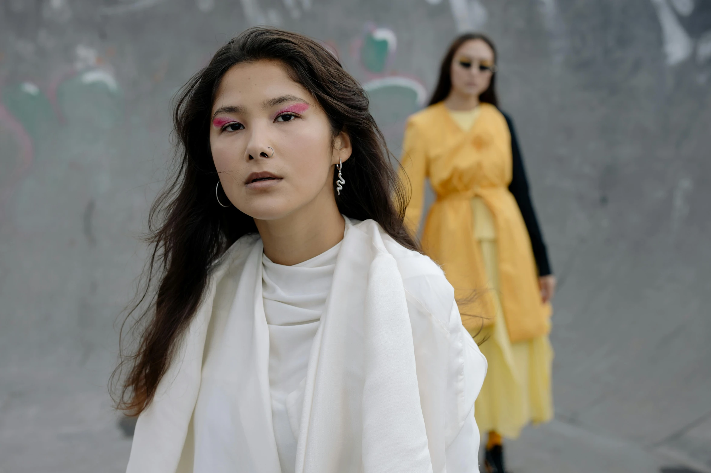 woman with makeup on her face walking with a girl in yellow behind her