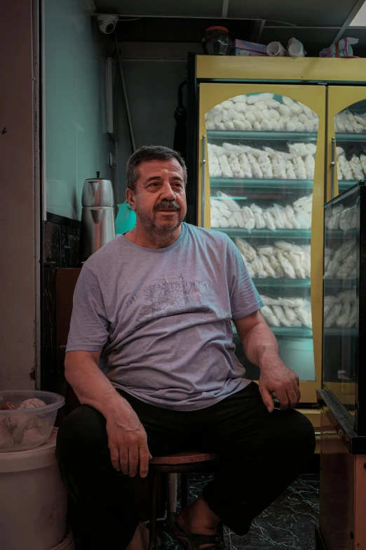 a man sits at a counter in front of glass cases