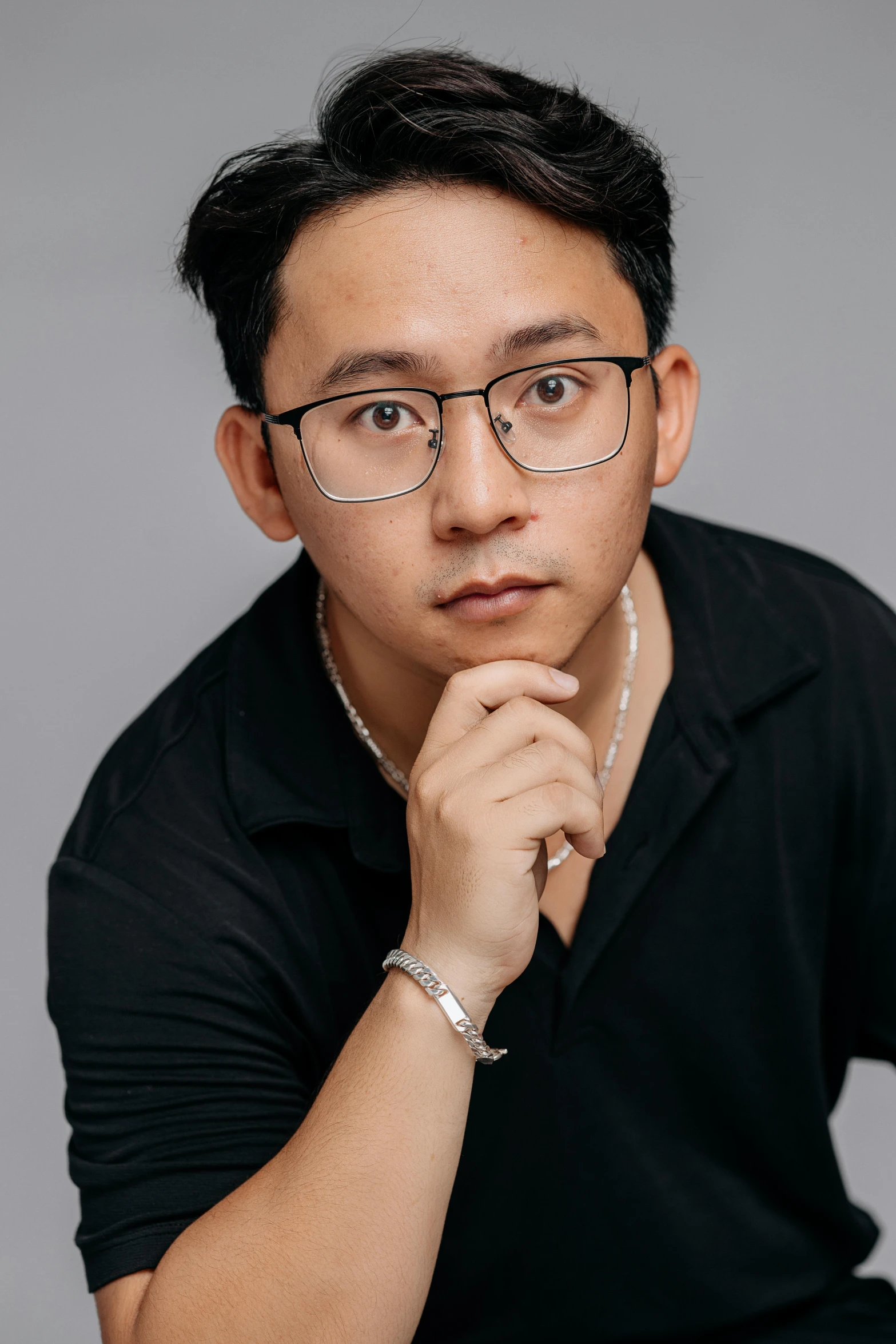 a man in a black polo shirt with his hand to his chin