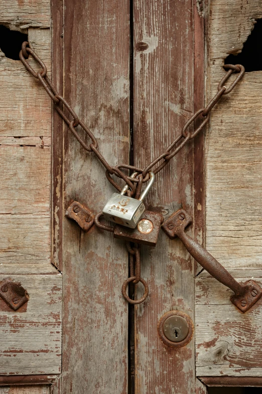 a padlock on an old wooden door with rusted chains and keys