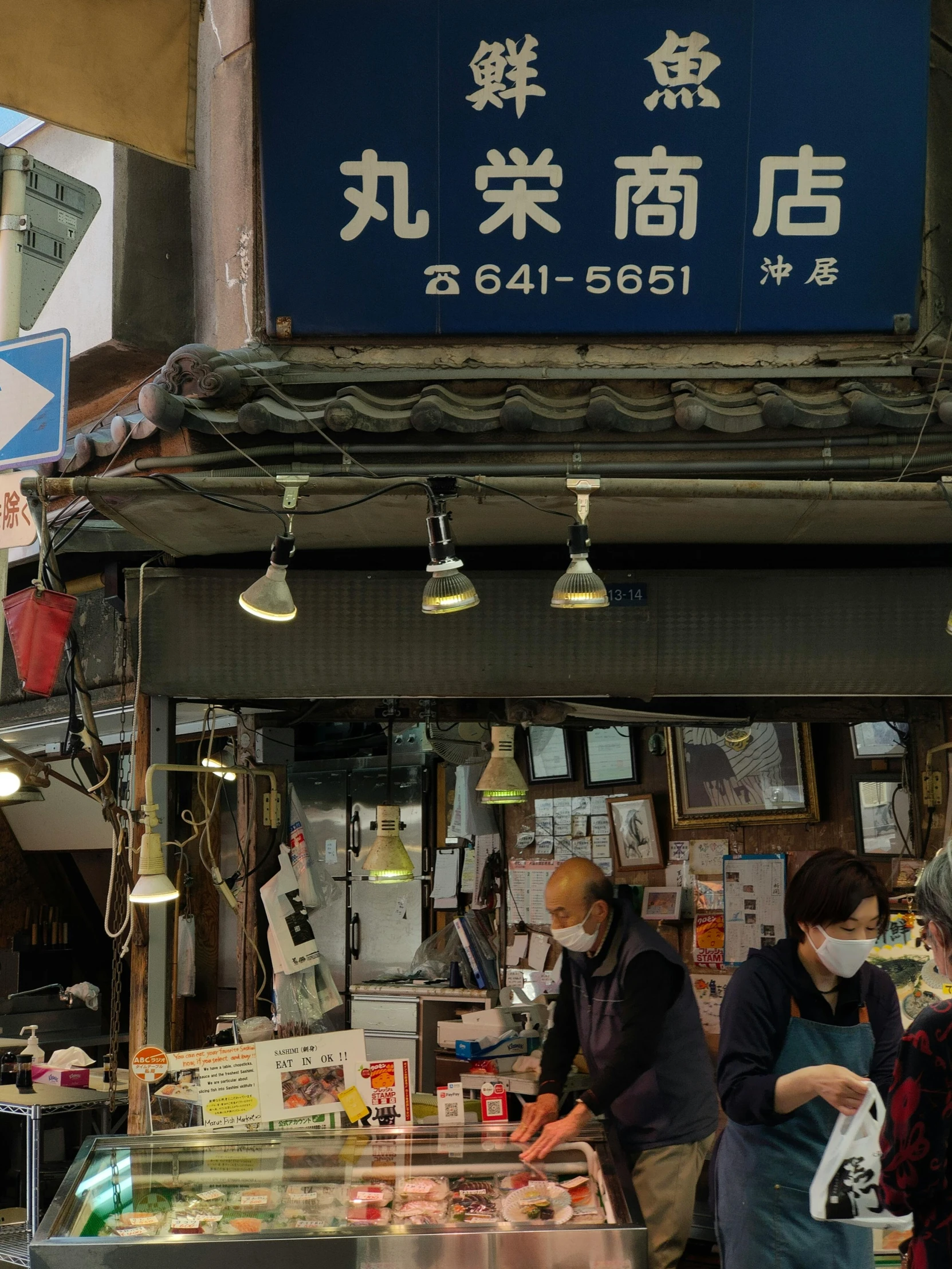 people wearing face masks while looking at food on the counter