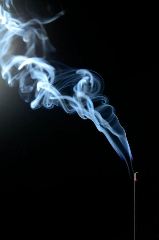 a white smoke billowing out of a pipe on a dark background