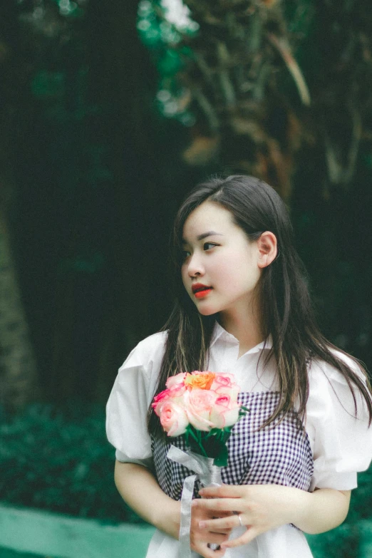 an asian girl holding a flower in her hand