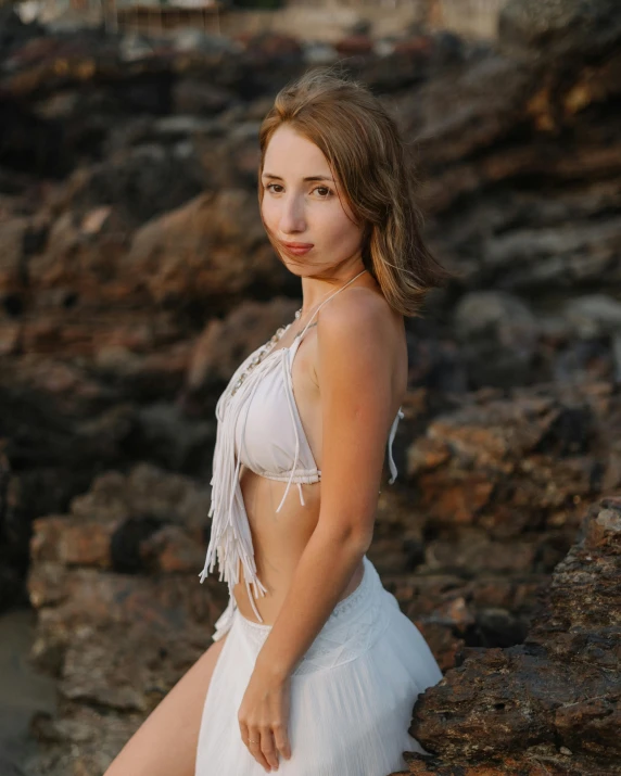 a beautiful woman standing next to a rocky beach