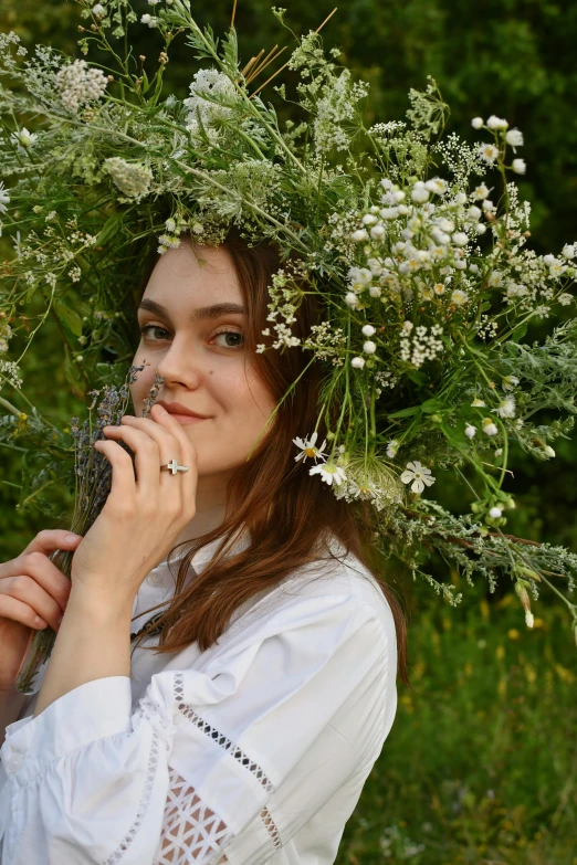 woman in white shirt surrounded by greenery with flowers