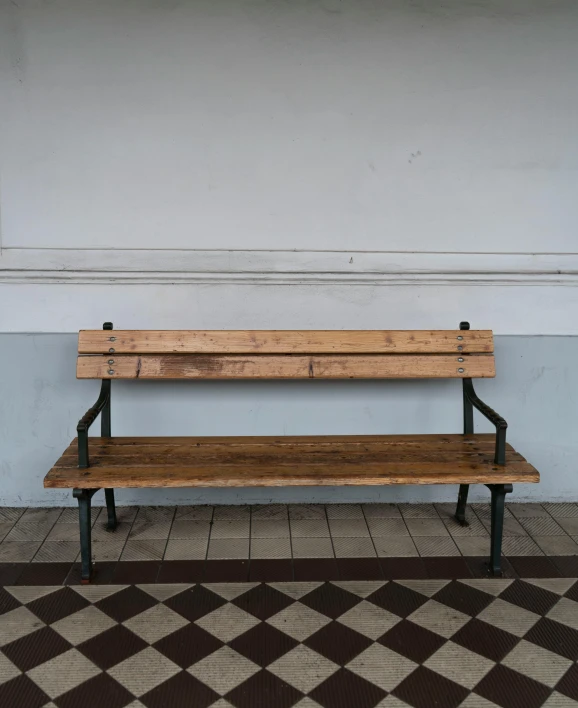 a wooden bench on a tiled floor near a building