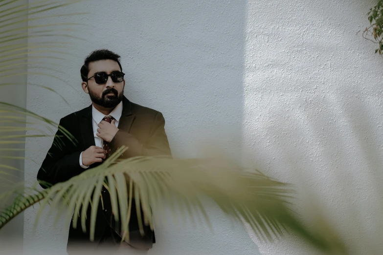 a man with a beard and sunglasses on holding a tie