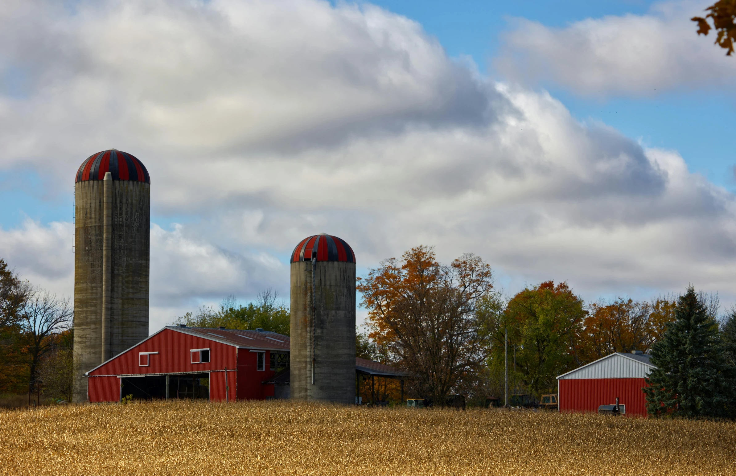 a barn on a farm with two large red barnes
