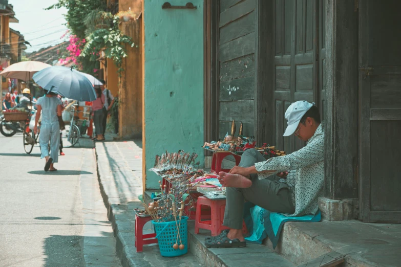 a man sits at his street corner with an umbrella