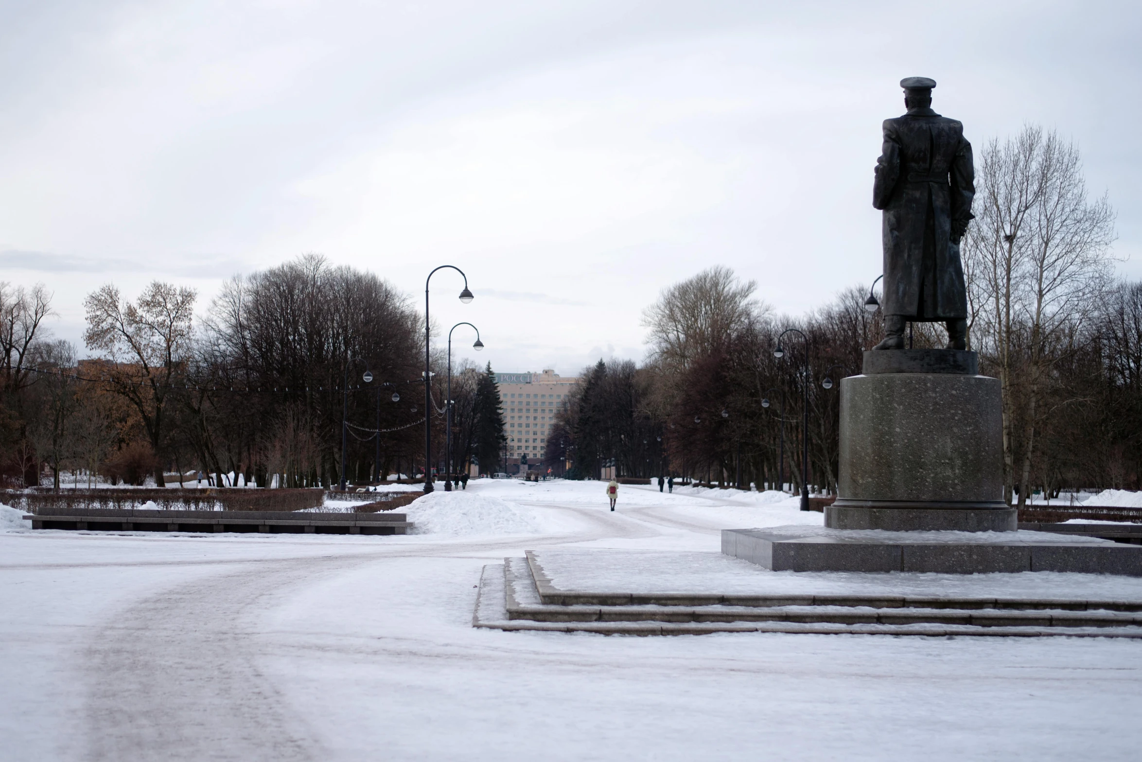 a walkway that has snow on the ground and two statues