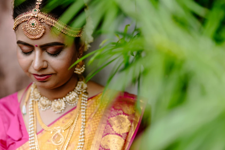 a bride poses for the camera wearing gold jewelry