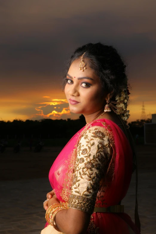 an indian woman posing in traditional garb at sunset