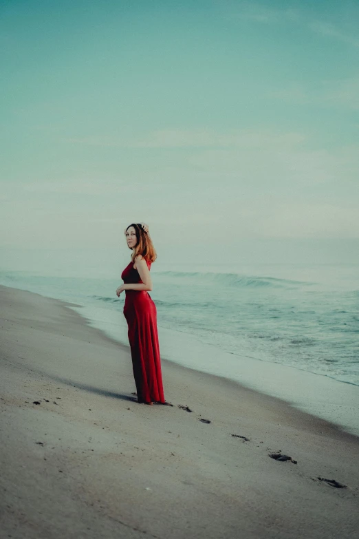 a woman standing on the beach looking into the ocean