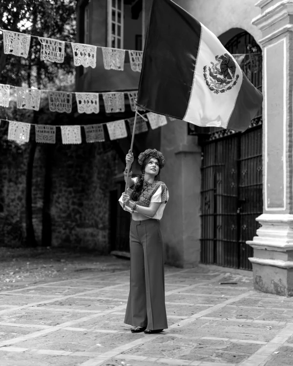 a woman holding a mexican flag on top of a stone floor