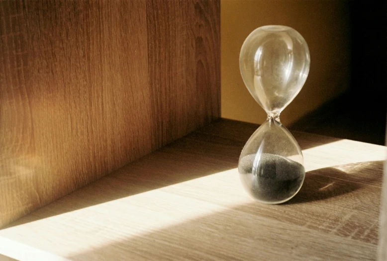 a sand - glass hourpiece with a shadow on a shelf