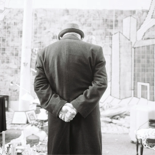 black and white pograph of a man standing near a tv