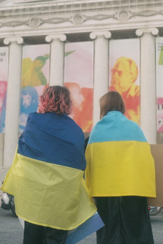 two women walking next to each other with large scarves on their shoulders