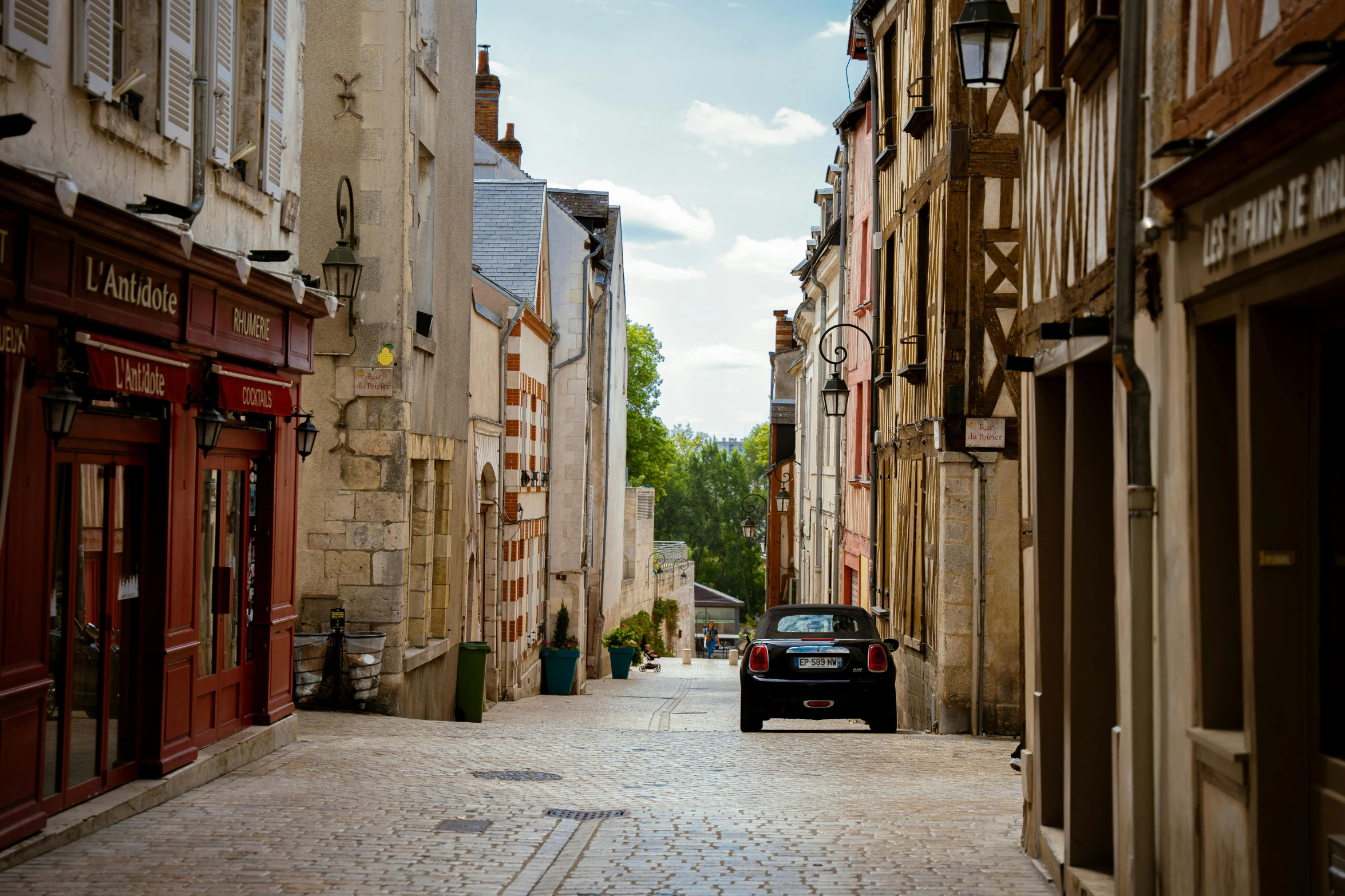 an old fashioned black car driving down a street