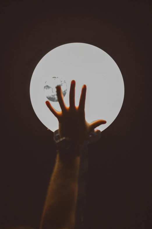 a person holding their hand up towards the moon