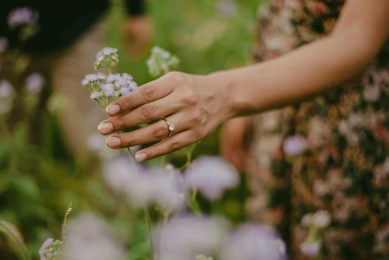 a woman in a dress and ring holds a flower