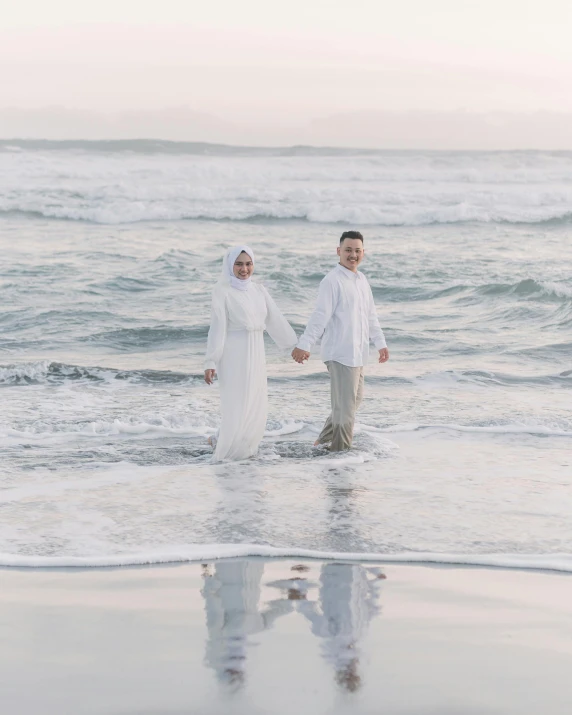 two people holding hands while walking in the ocean