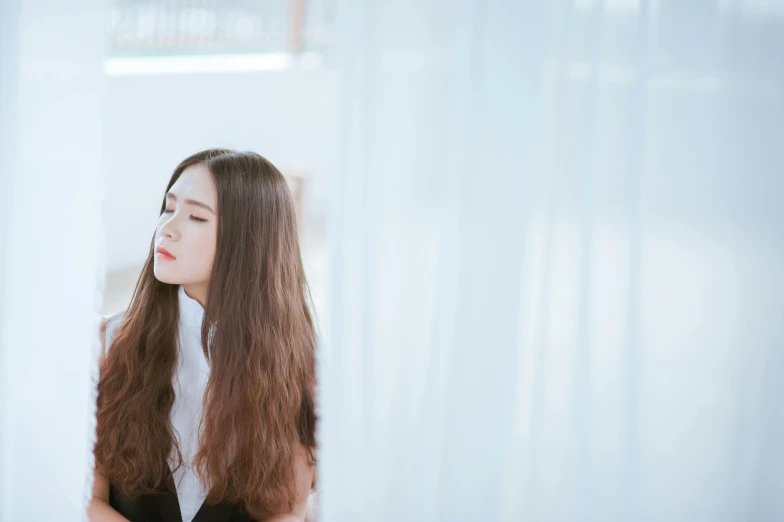 a woman with long hair standing by the wall