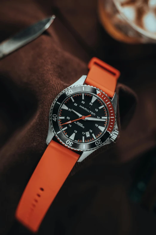 a watch with an orange strap on top of it
