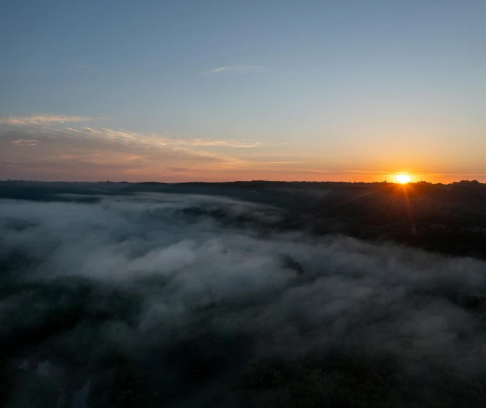 a sunset over the clouds over a forest