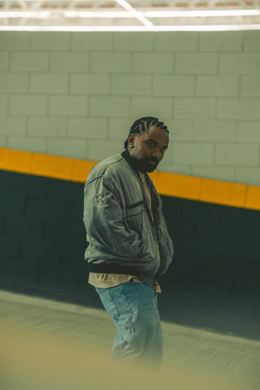 a man in grey jacket next to wall with white brick