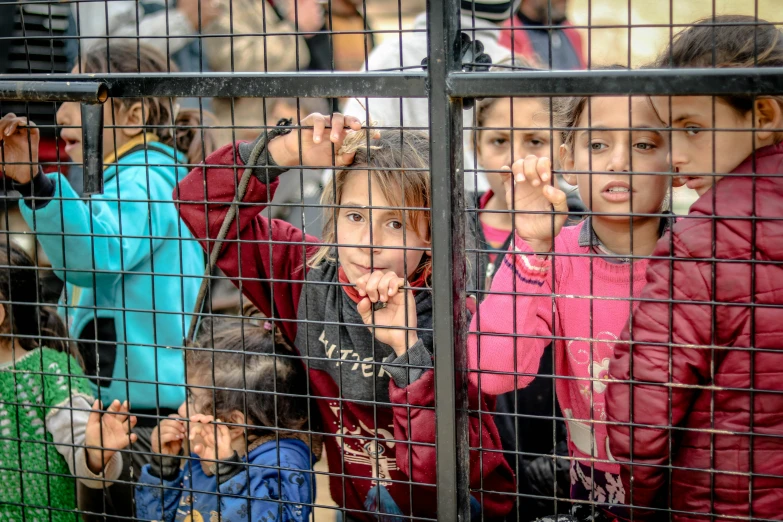 children in cages looking through them at soing