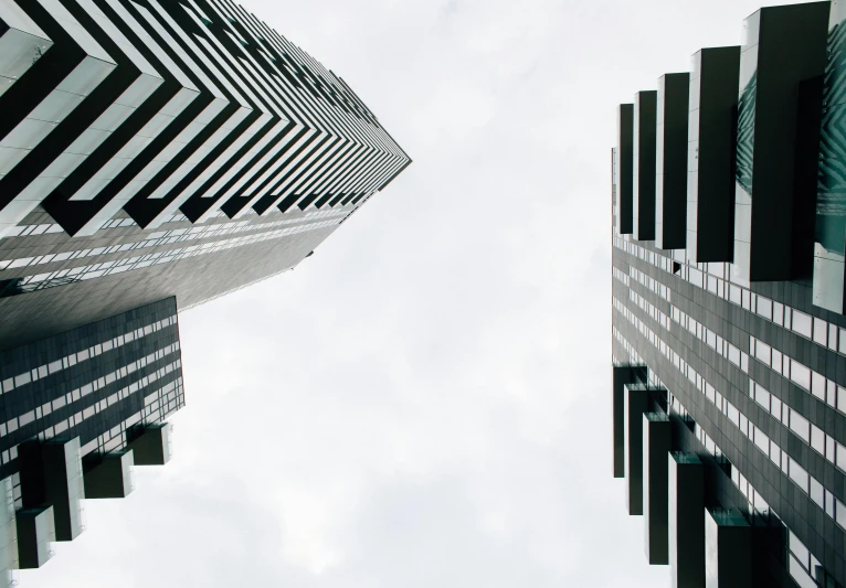 the tops of several tall buildings against a cloudy sky