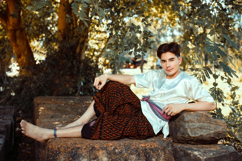 a man wearing a tie sitting on the edge of a rock