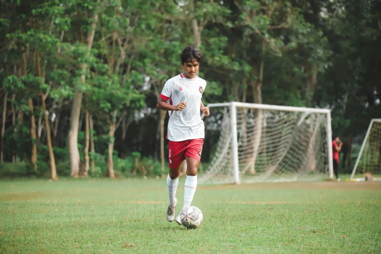 a young soccer player in red is kicking the ball