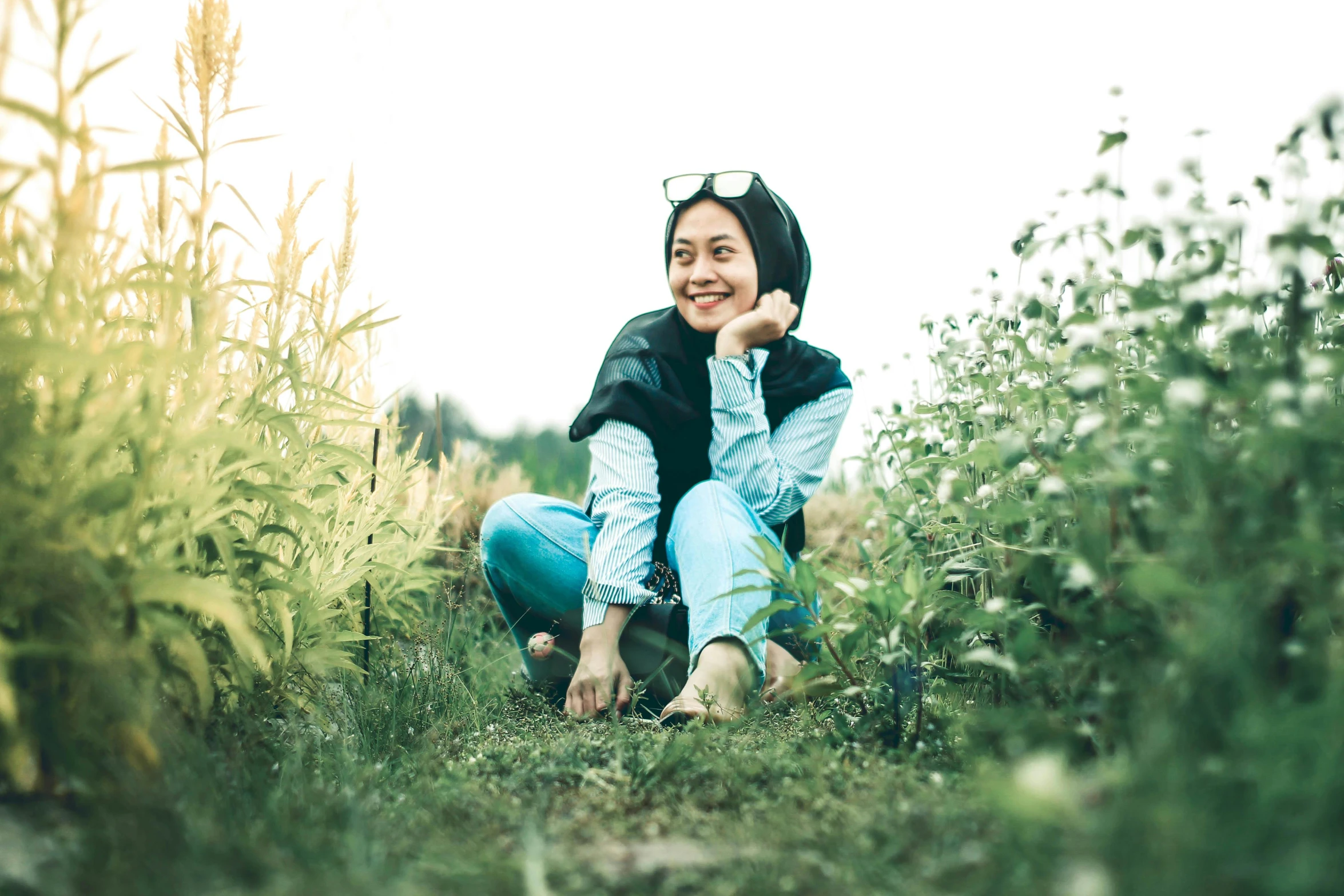 the woman is sitting in the grass posing for the camera