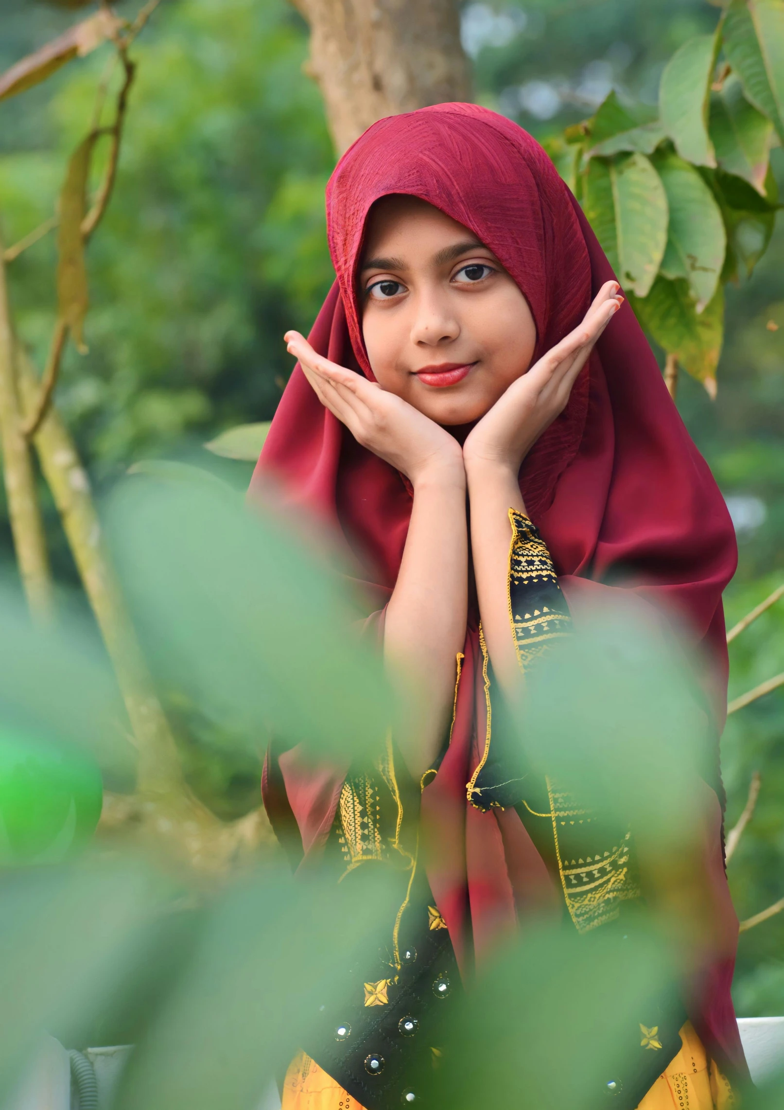 a girl in a red headdress poses under a tree