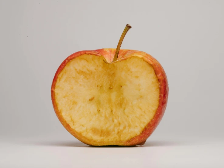 an apple cut in half on a white surface