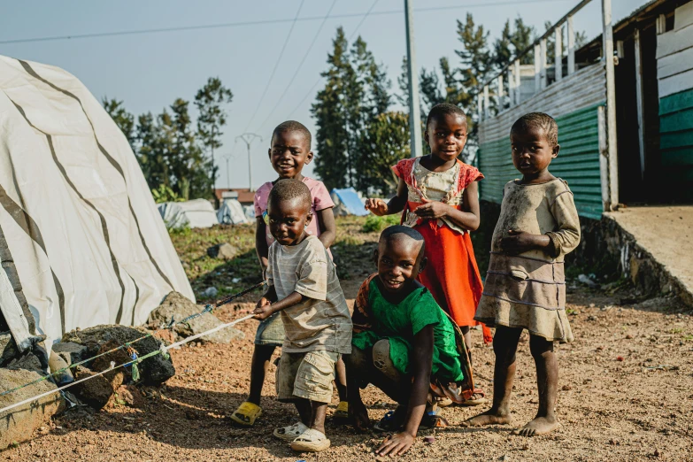 four children pose for a picture in a dirt yard