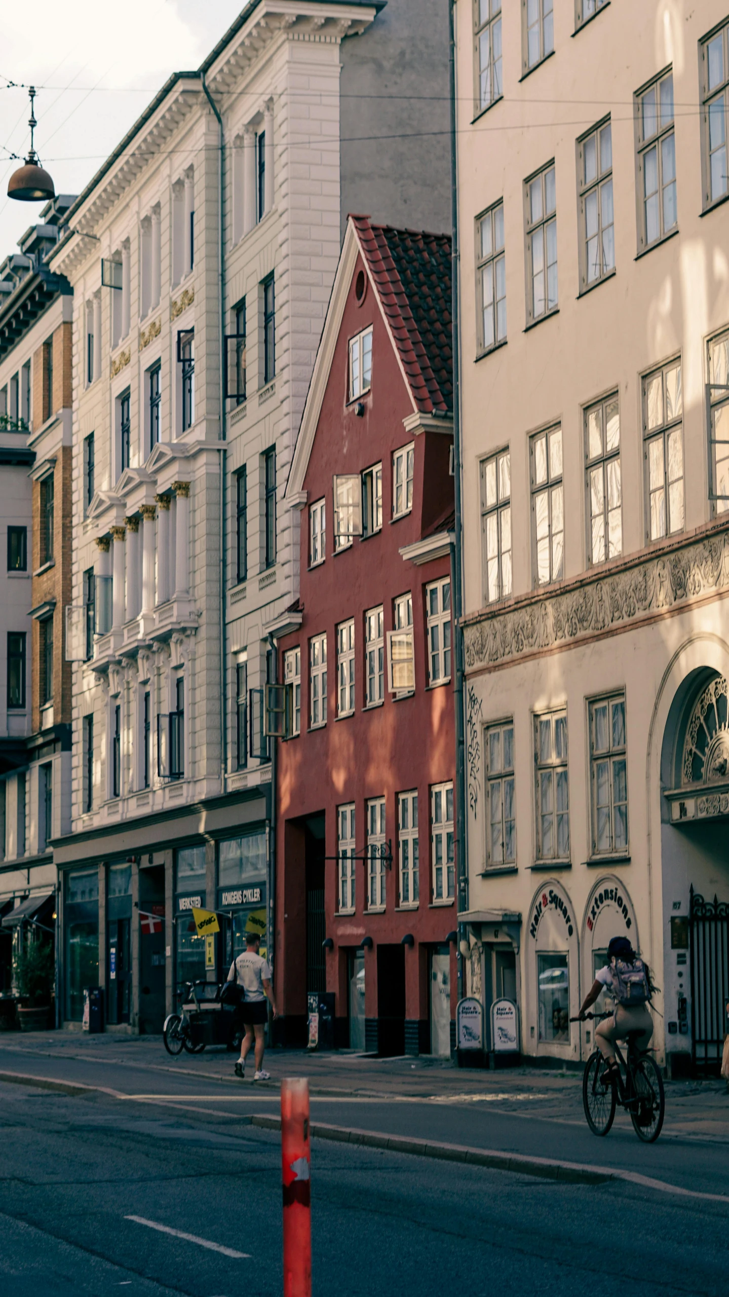 a group of buildings and people on bicycles crossing the street