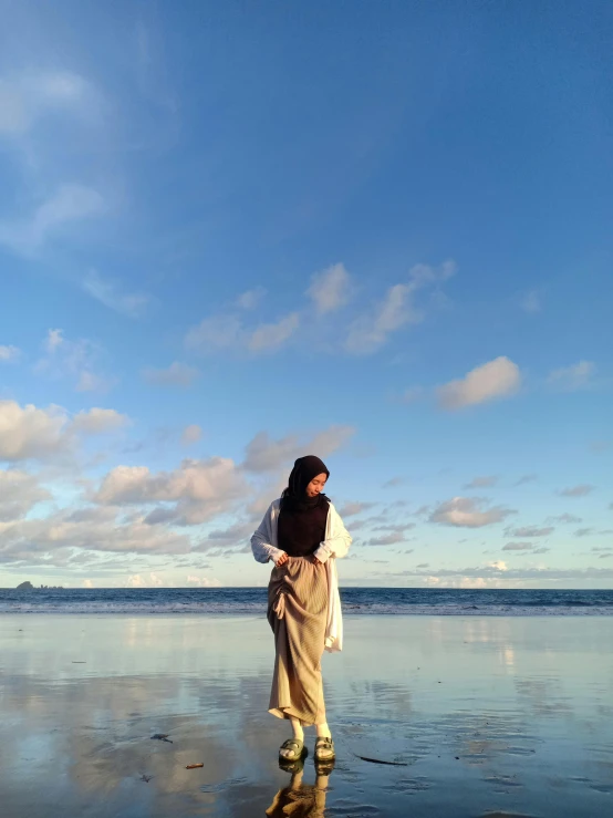 a woman standing on top of a beach near the ocean