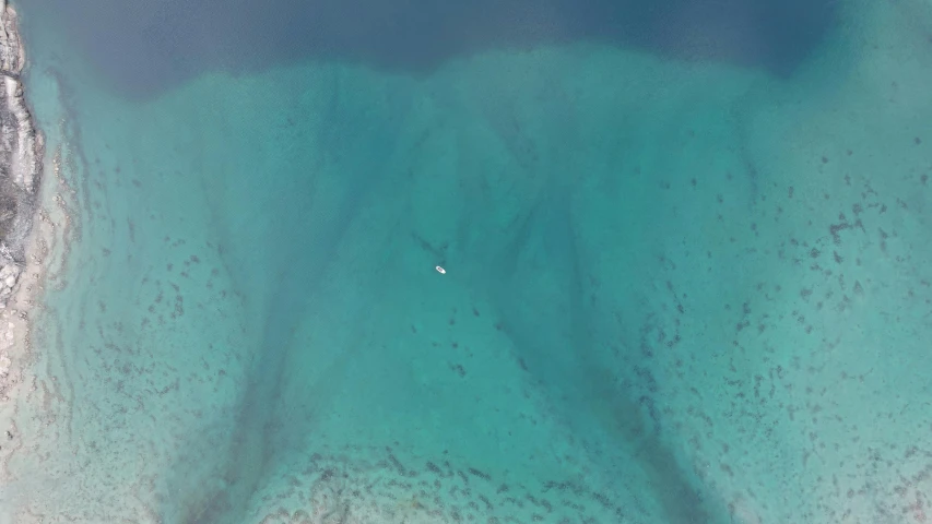 an aerial view of the blue ocean with a boat in it