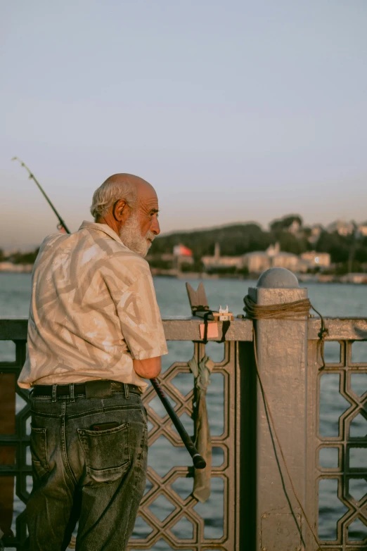 a man standing next to the side of a bridge while holding a fishing rod