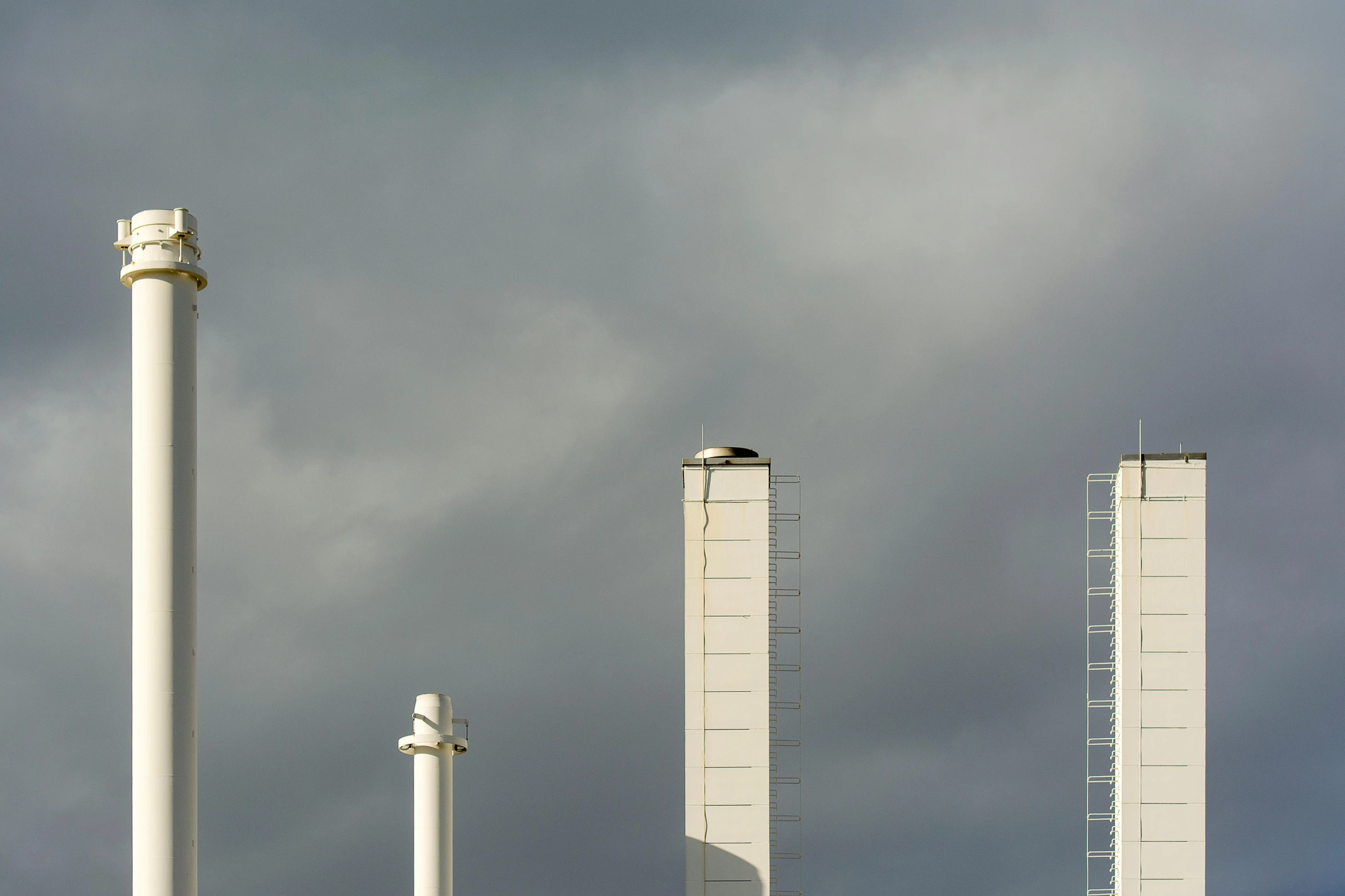 an airplane flying in a cloudy sky next to buildings