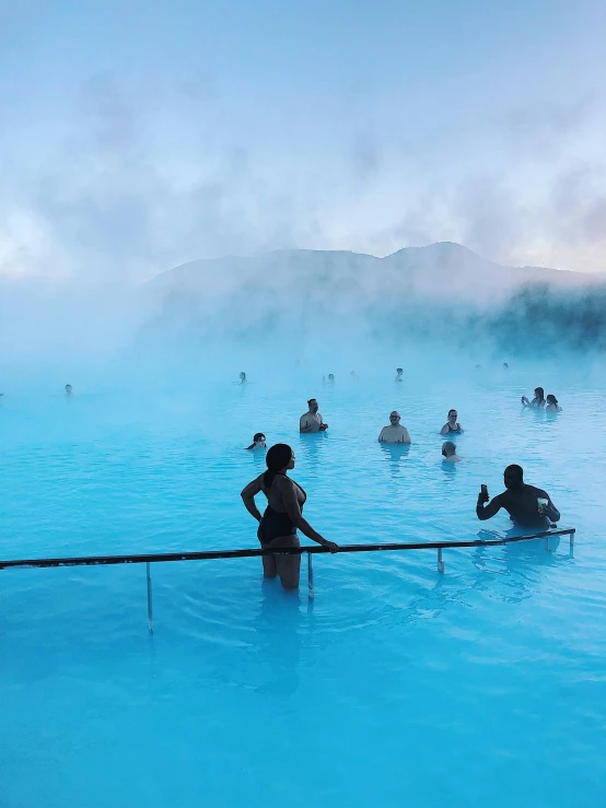 people swim in the blue water at an outdoor swimming pool