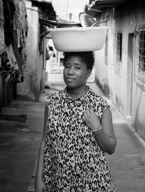 a woman walking down a street carrying a hat on her head