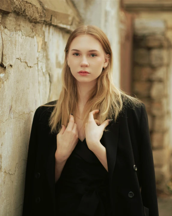 a woman standing next to a wall wearing a suit and tie