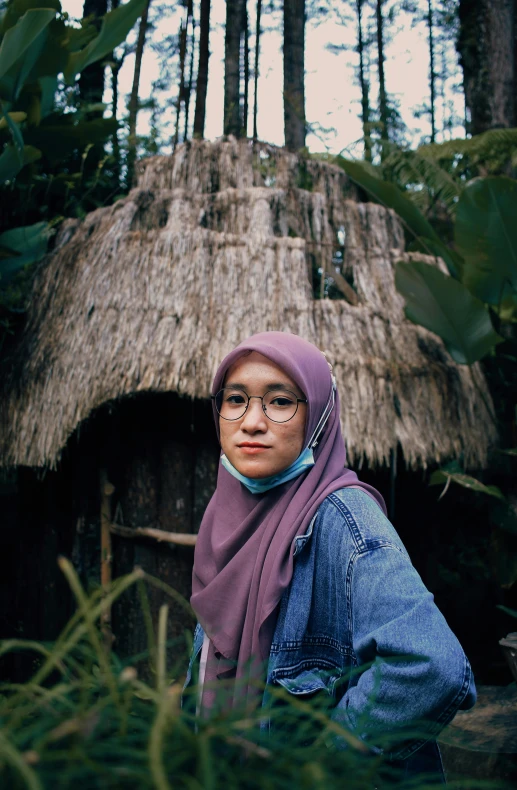 the woman is in front of her thatched hut