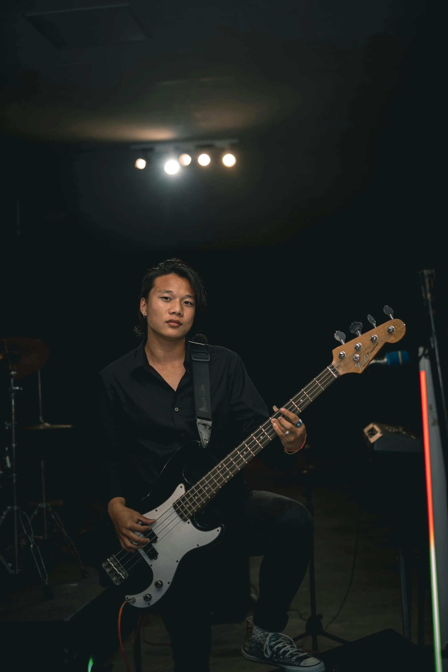 a young woman sitting with an electric bass guitar