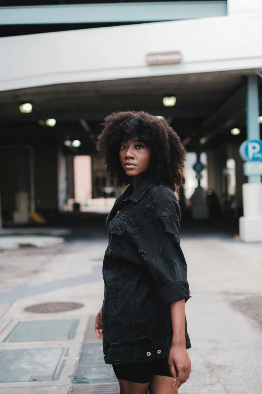 a woman that is standing in front of a street sign