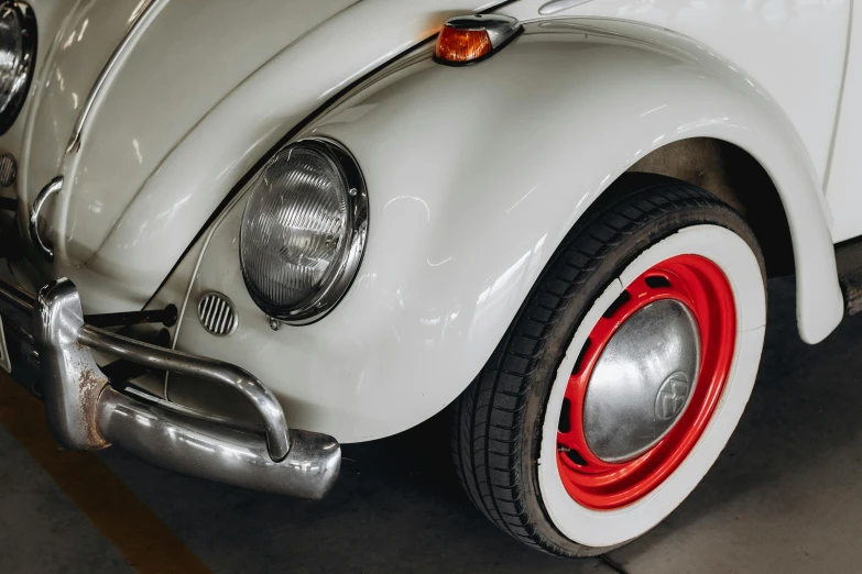 close up of white volkswagen type beetle with red spokes