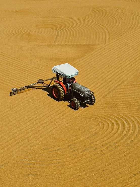 a tractor being driven across a large, sandy field